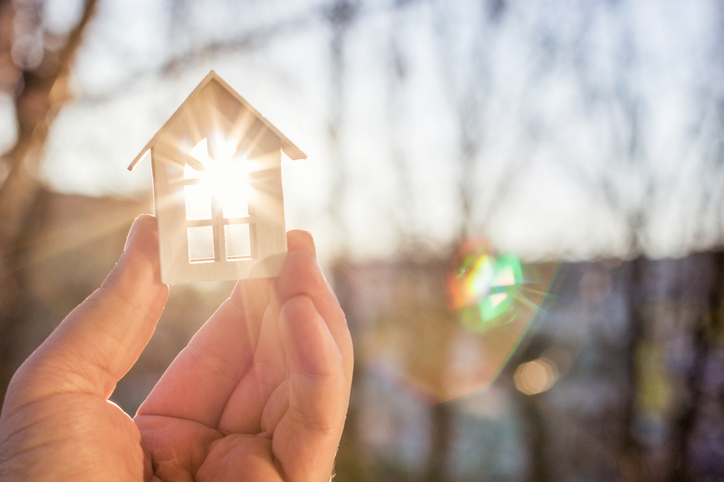 House in hand in the rays of the sun. The concept of unoccupied property insurance.